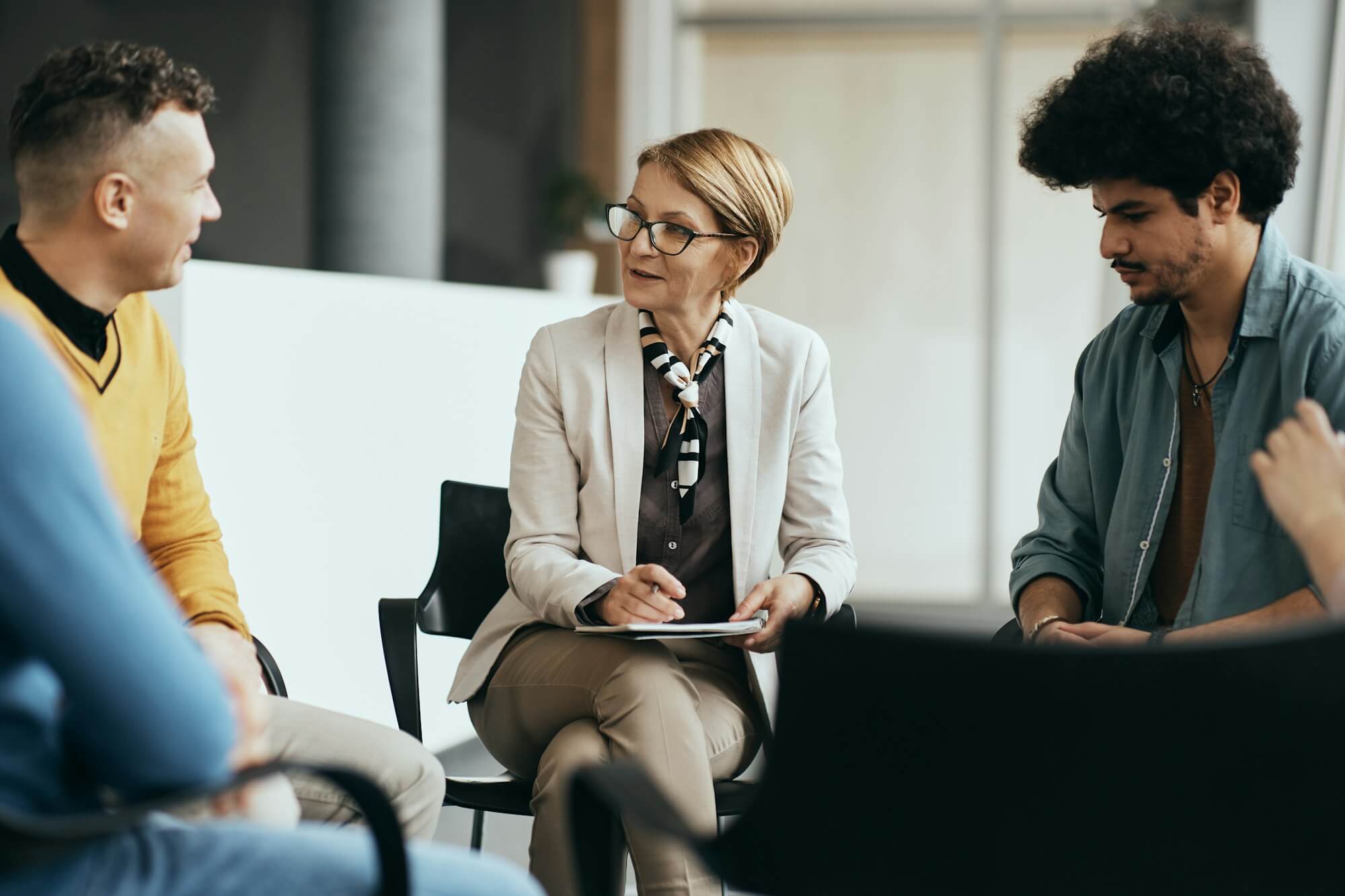 mature-therapist-talking-to-participants-of-group-therapy-at-mental-health-center-.jpg
